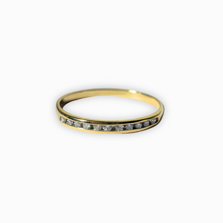 A yellow gold ring featuring a channel-set row of small clear gemstones on the front, photographed against a clean white background.