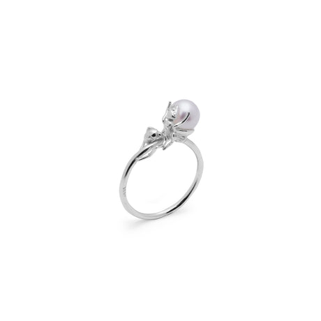 A silver ring with a small sculpted ant design holding a natural freshwater pearl on its back, with a smooth white band.